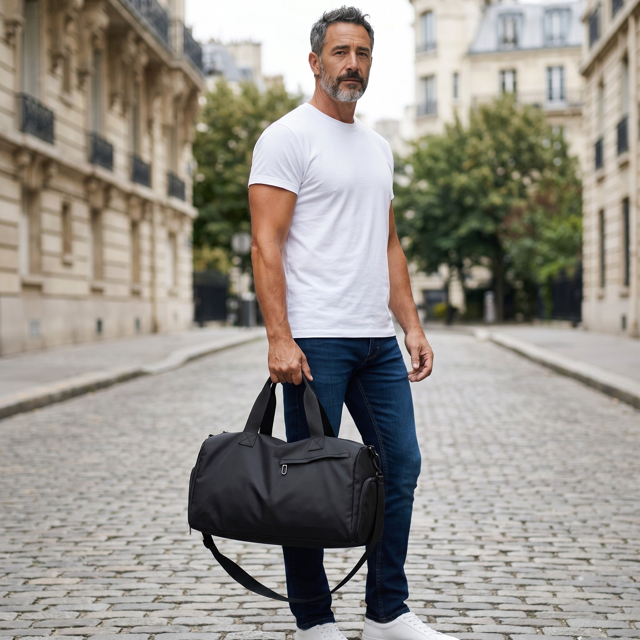 Homme portant un sac de sport noir Le Voyage Prestige, imperméable, idéal pour le fitness et les voyages. Image